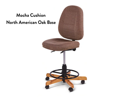 The Koala SewComfort Chair features an ergonomic tall backrest, mocha cushion, and a North American oak wood base with five wheels and a black circular footrest. Text on the left reads: “Mocha Cushion North American Oak Base.”.