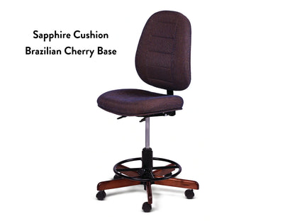 The Koala SewComfort Chair features a blue Sapphire Cushion, ergonomic design, round footrest, and a Brazilian Cherry wooden base on wheels. Text on the left reads: Sapphire Cushion Brazilian Cherry Base.