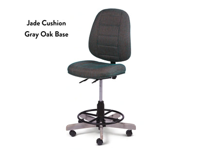The Koala SewComfort Chair features a jade-colored cushioned seat and backrest, adjustable height, foot ring, and a gray oak five-wheel base—ergonomic for long crafting. "Jade Cushion Gray Oak Base" is printed on the left side.