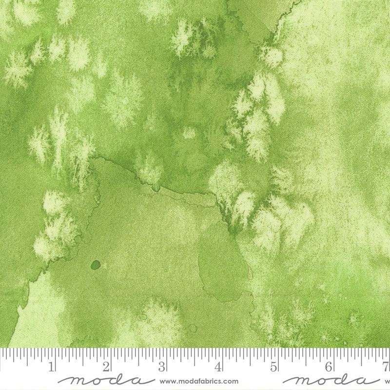 Soulstice Flow Line Fabric Yardage by United Notions features mottled green watercolor textures with light and dark patches. Inch ruler markings along the bottom edge make it ideal quilting cotton for your next project.