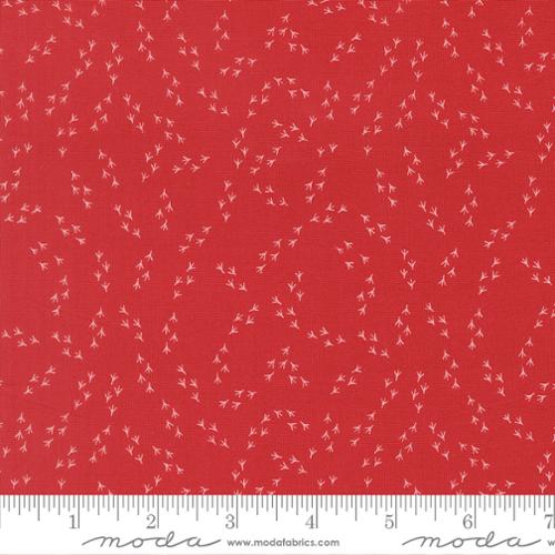 The Henhouse Chicken Feet Barn Fabric Yardage by United Notions features red quilting cotton with small, light pink leafy branches in curved lines. Shown with a white ruler for scale, it's perfect as a Chicken Feet Blender or farmhouse accent.