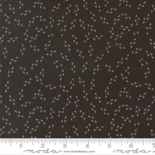 Dark brown quilting cotton called “The Henhouse Chicken Feet Iron Fabric Yardage” by United Notions, features small white bird tracks scattered throughout. Inches are shown for scale at the bottom of the image.