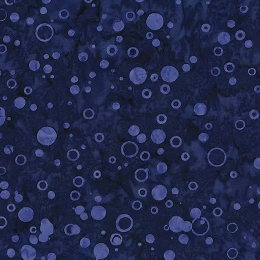 The Bubbles Grape Batik Fabric Yardage features a dark blue textured background with randomly scattered lighter blue circles and rings, creating a bubble-like, abstract pattern inspired by grape batik designs.