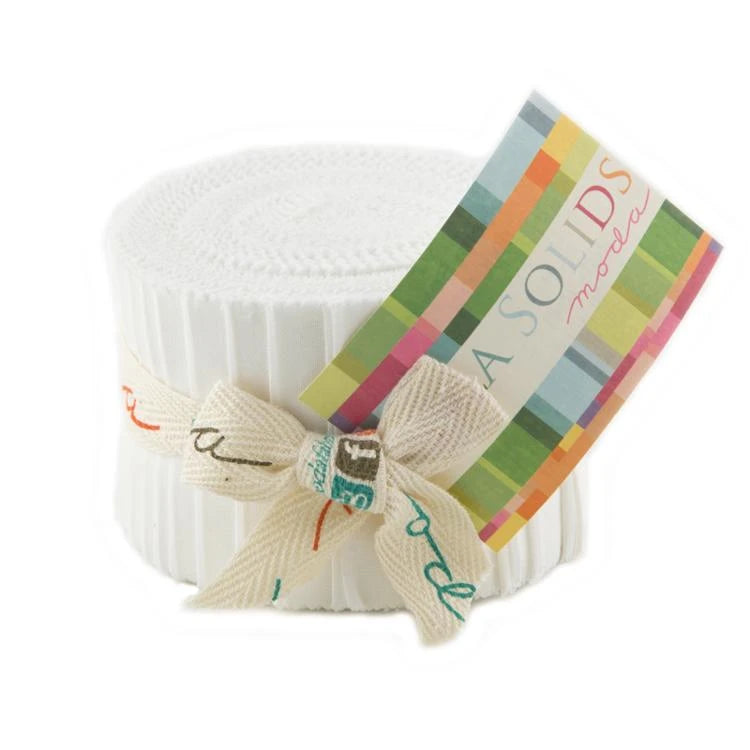 A bundle of Bella Solids White Bleached Junior Jelly Roll fabric strips by United Notions, tied with a cream ribbon featuring multicolored text and a colorful BASOLIDS moda label.