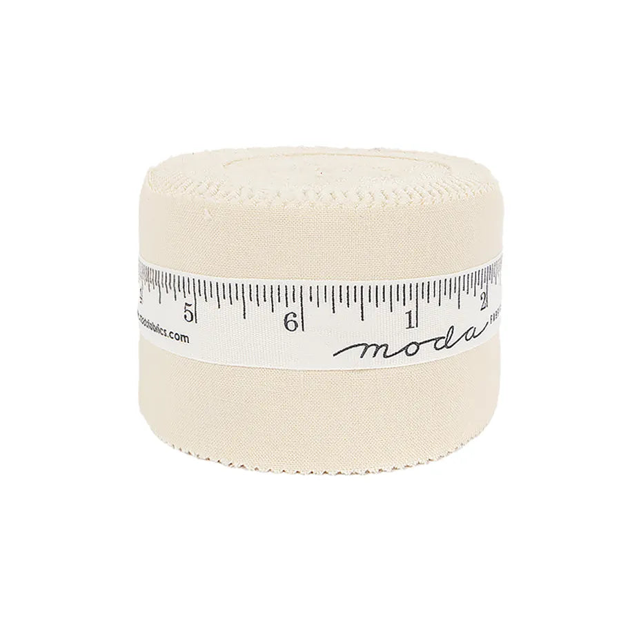 A rolled bundle of Bella Solids Natural Junior Jelly Roll by United Notions, secured with a white ribbon featuring black ruler markings and "moda," is arranged in a cylinder shape against a white background.