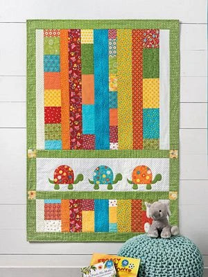 The Fast & Fun Quilts for Kids by Brewer Sewing features colorful vertical patchwork strips, a green border, and three cartoon turtles appliquéd at the bottom—perfect for children’s rooms with toys and books.