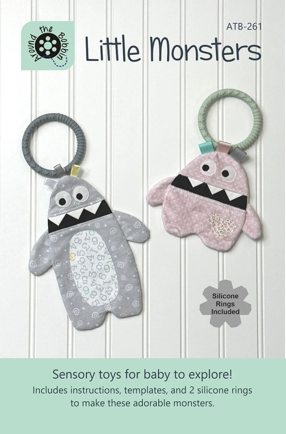 Checker Distributor's Little Monsters Pattern features two plush monster-shaped sensory baby toys, one gray and one pink, each with baby-safe silicone rings for safe, engaging play. Perfect DIY sensory toys for infants.