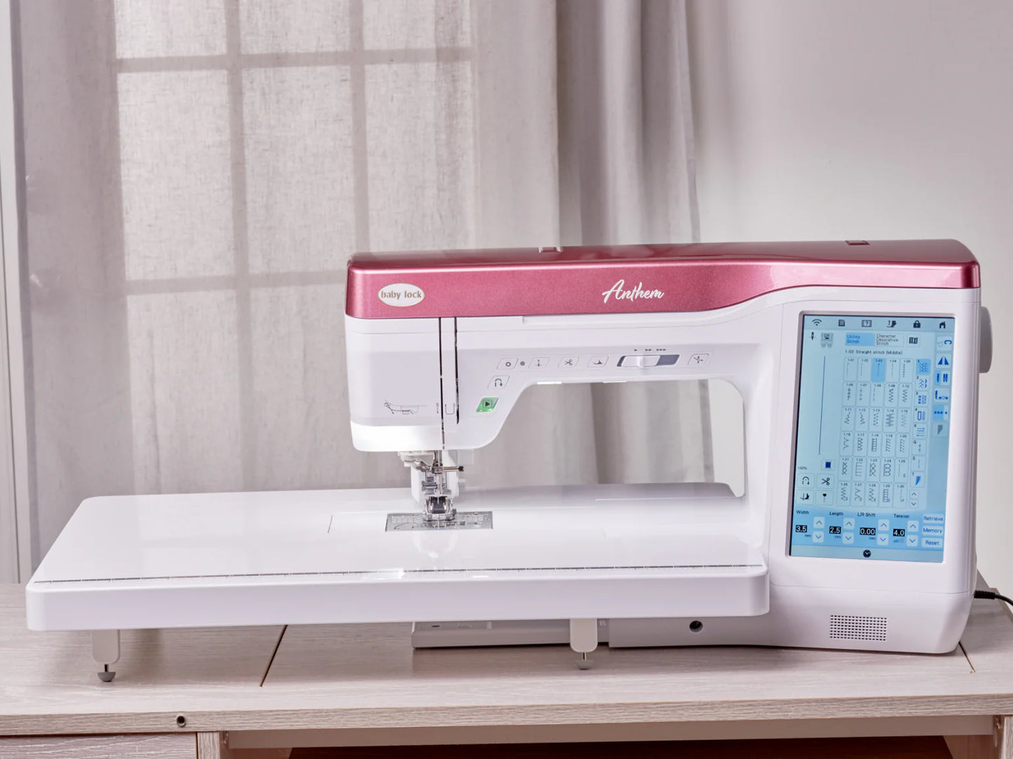 A Baby Lock Anthem Sewing & Quilting Machine with FREE 60 Days of Online Classes, featuring a pink and white design, StitchSync Regulation, a large right-hand touchscreen, and an extended work surface sits on a table in natural light.