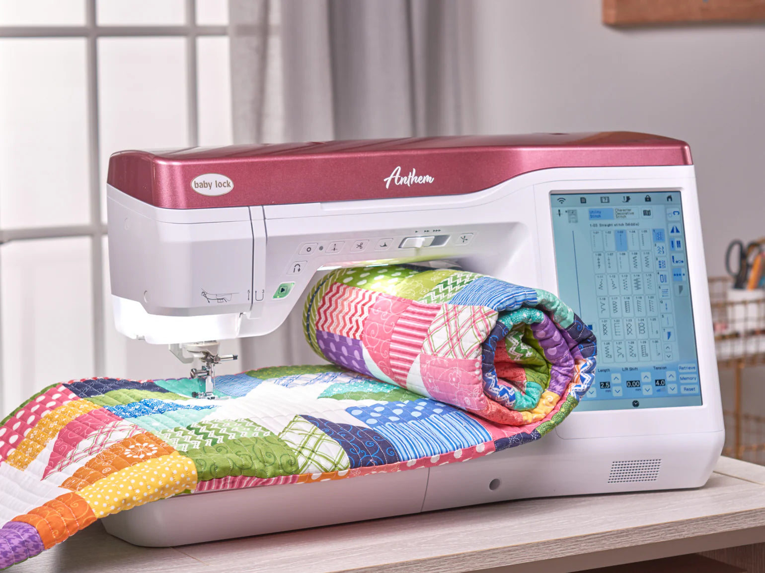 A Baby Lock Anthem Sewing & Quilting Machine with FREE 60 Days of Online Classes, featuring a red and white exterior and digital StitchSync Regulation display, stitches a colorful patchwork quilt as sunlight spills through a window.