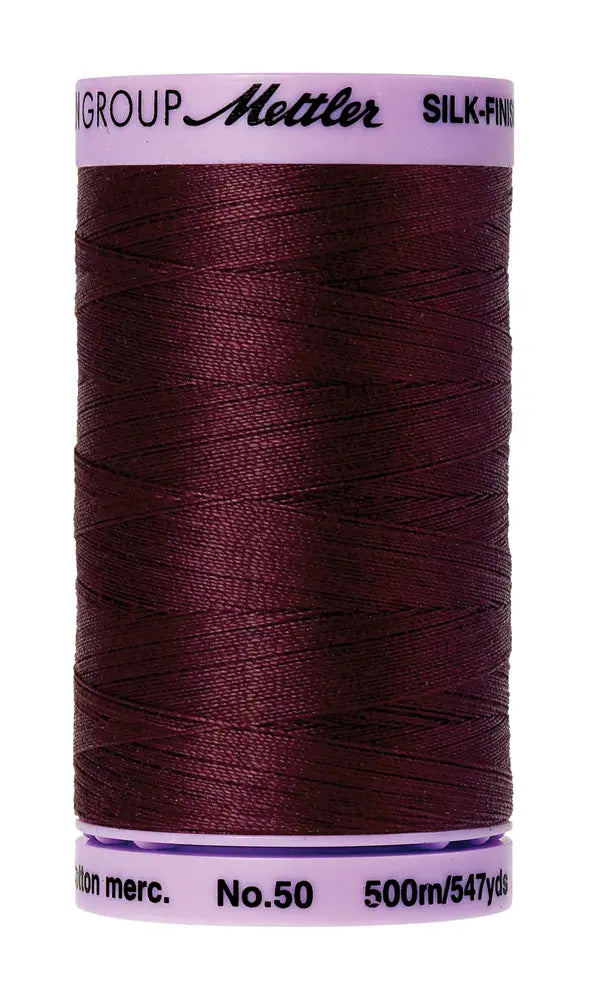 A spool of Mettler Cotton Silk Finish 50wt 500m in Beet Red, ideal as cotton sewing or quilting thread. Each spool is marked 500m/547yds and No.50 on the ends.
