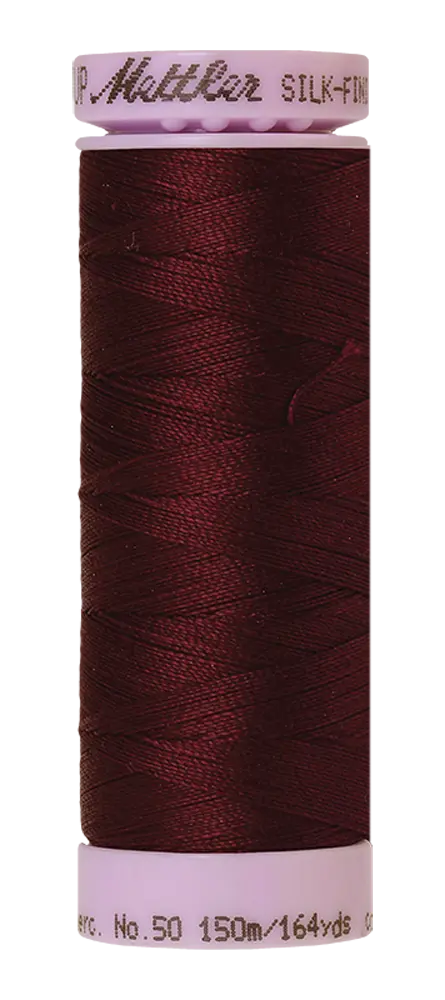 A spool of Mettler Cotton Silk Finish 50wt 150m Beet Red thread, dark red with white plastic ends, featuring brand and length details in gray text.