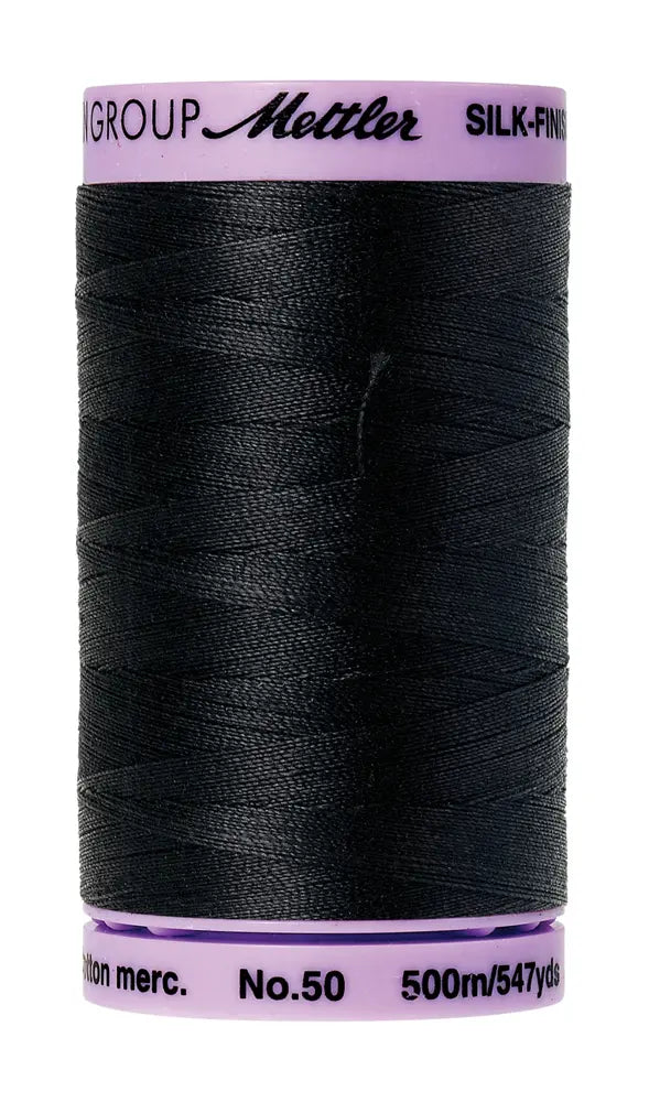 A 500m spool of Mettler Cotton Silk Finish 50wt sewing thread in black, featuring a purple label with brand details. Ideal for quilting projects.