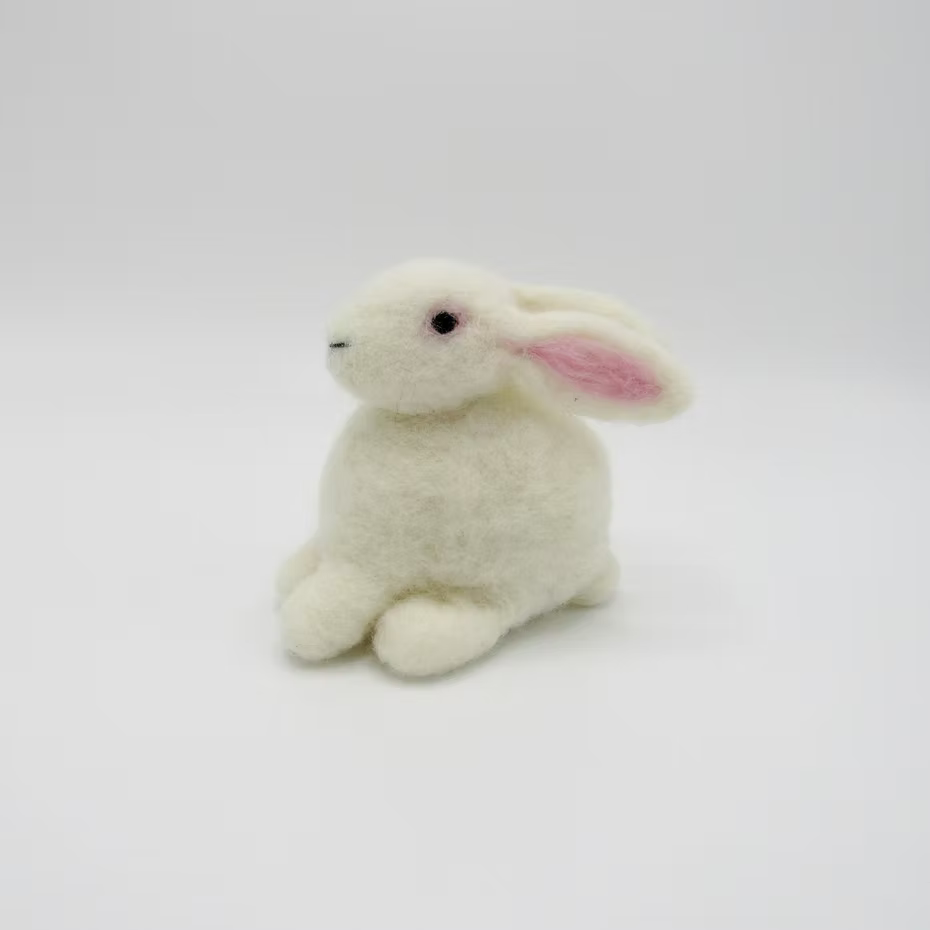 The Feather Felts Bunny - Needle Felting Kit No Foam features a small, plush white rabbit with pink ears, ideal for bunny needle felting projects. The rabbit sits on a plain white background, facing slightly left with a soft, fluffy texture.