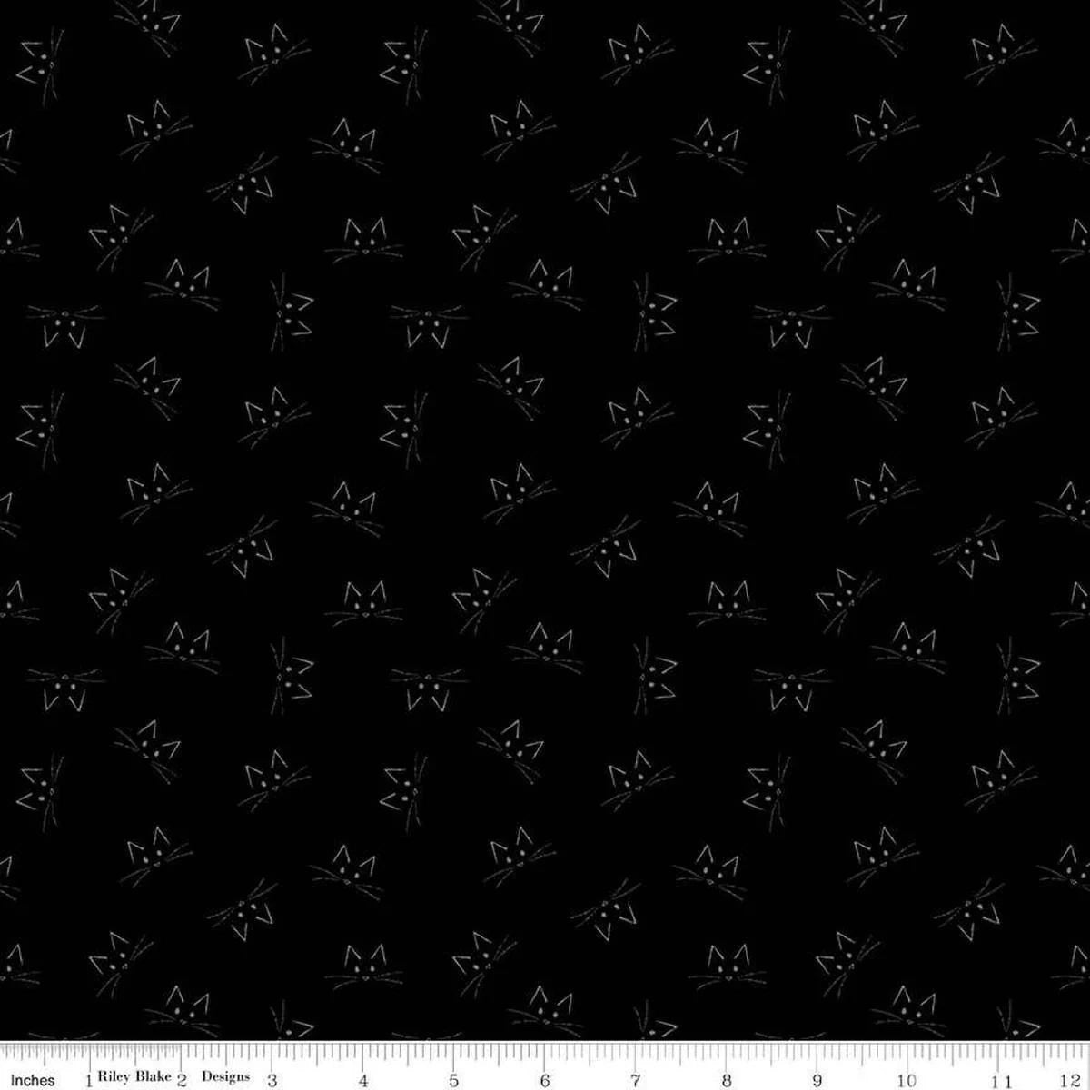 Blackout Black Cat Face Fabric Yardage by Riley Blake features a repeating pattern of simple white cat faces on black. A white inch ruler at the bottom shows scale—ideal for Halloween quilting or black cat-themed projects.