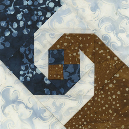 Create precise quilt blocks with spiral designs using blue, brown, and white patterned fabrics by trimming with the Checker Distributor Creative Grids Square on Square Trim Tool for 4in or 8in finished blocks.
