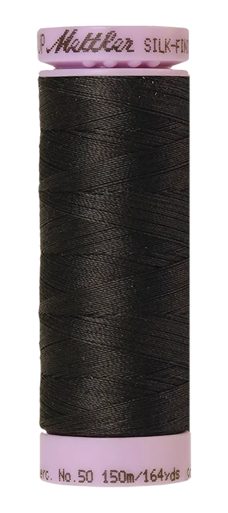 A spool of Mettler Cotton Silk Finish 50wt 150m thread in charcoal, featuring a black cotton color, light purple cap and base, with product details and length printed on the bottom edge.