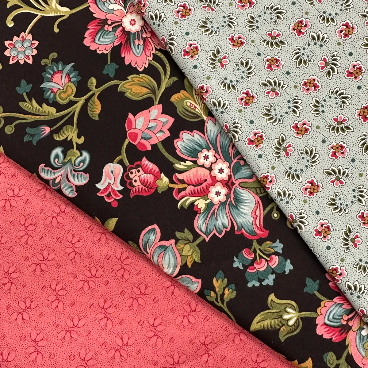 The Quilted Joy Collections for a Cause 3 Yard Quilt Top Bundle features three cotton fabrics arranged diagonally: pink with small flowers, black with large colorful blooms, and light gray with delicate florals.