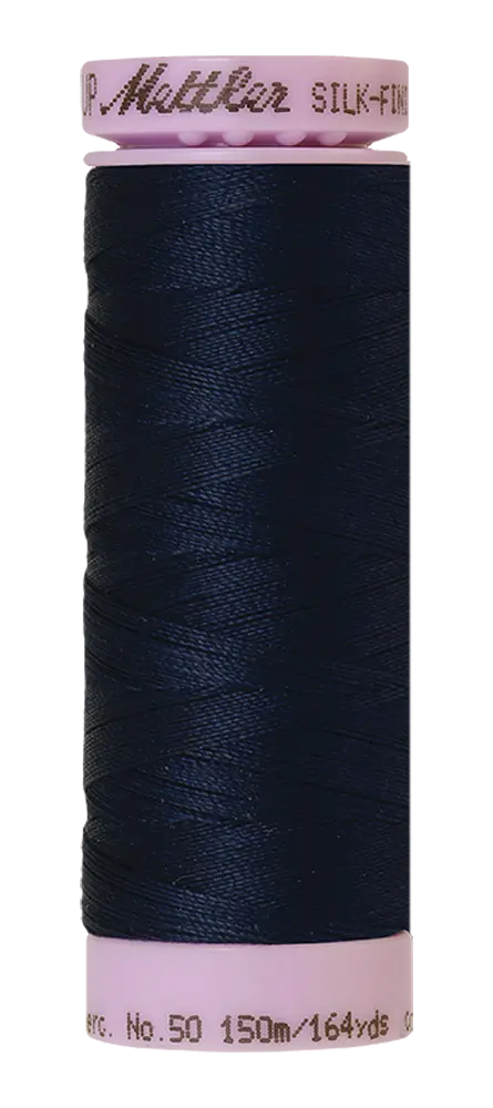 A spool of Mettler Cotton Silk Finish 50wt 150m Concord thread in dark navy blue with pale pink plastic ends, labeled with brand and length details.