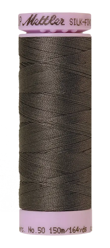 A spool of Mettler Cotton Silk Finish 50wt 150m Dark Charcoal sewing thread—perfect for quilting or any cotton project, with pink ends and text reading Mettler SILK-FINISH No. 50, 150m/164yds.