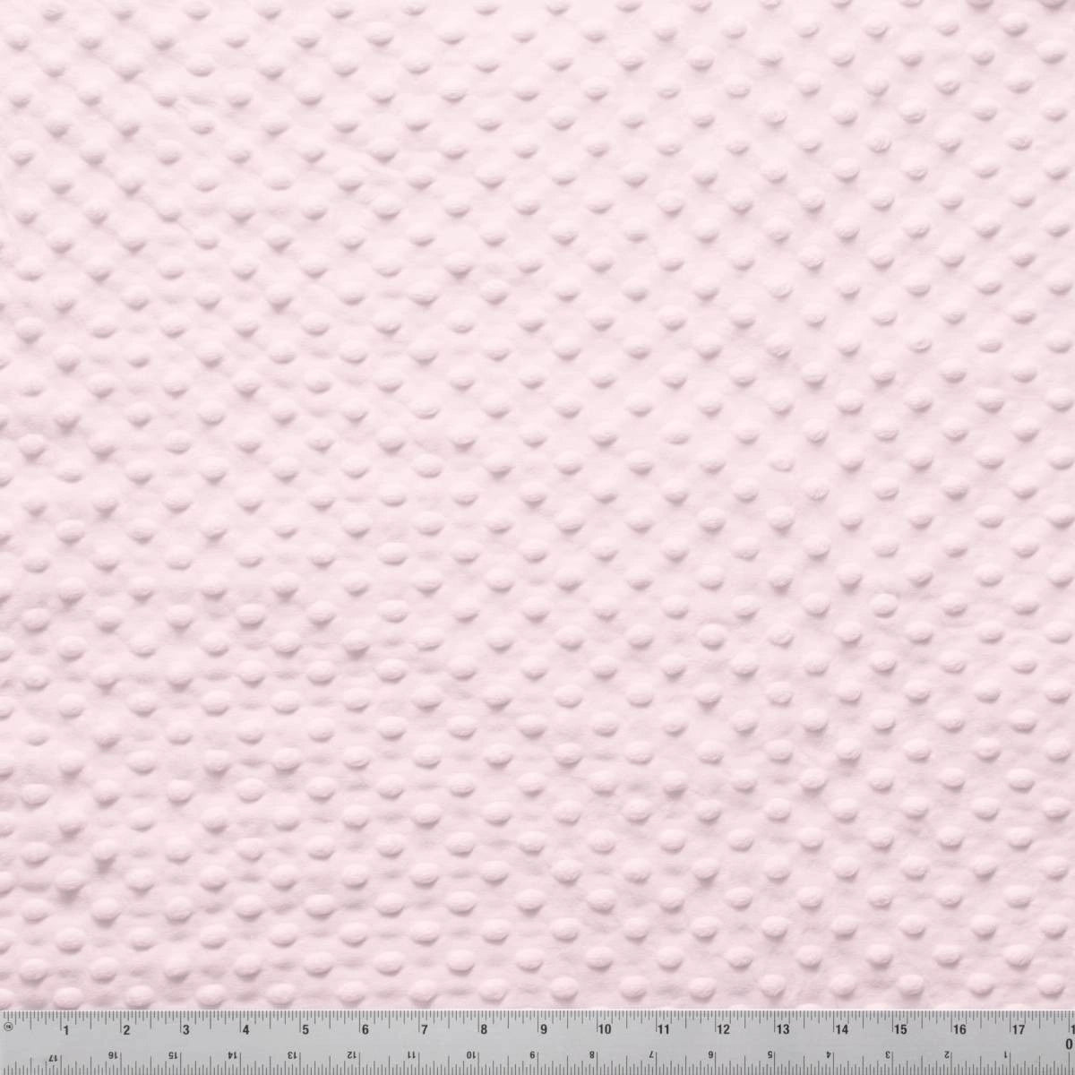 A close-up of Minky Dots Light Pink 60" Wide Quilt Backing Fabric by Jaftex - Henry Glass Fabrics shows its soft, raised dot texture—ideal for baby quilts. A ruler displays the scale in inches and centimeters.