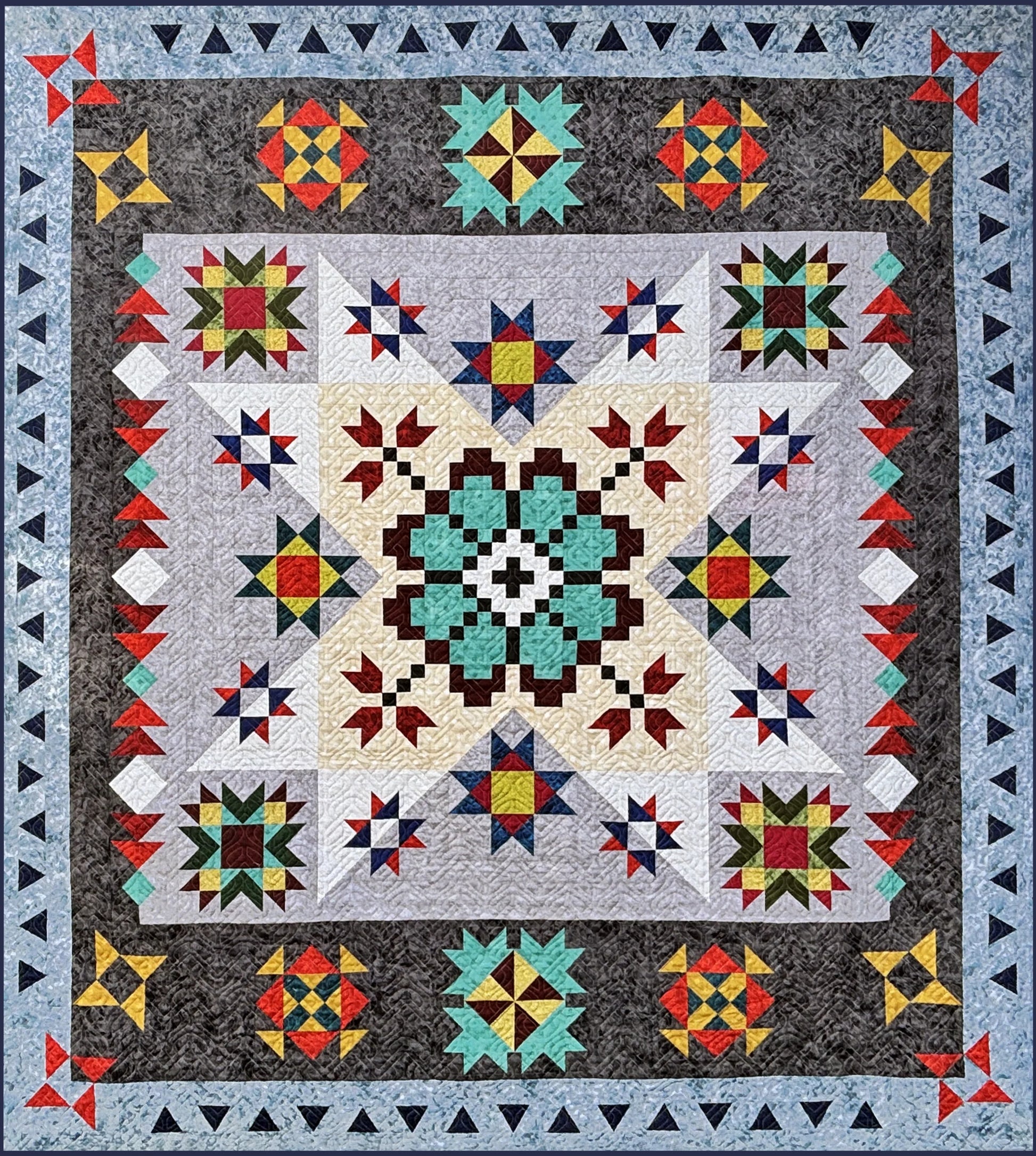 The Echoes of Iceland Block of the Month Kick Off by Quilted Joy features a vibrant patchwork quilt with intricate geometric patterns, a bold teal and black central motif, star shapes, and angular blue-gray borders.