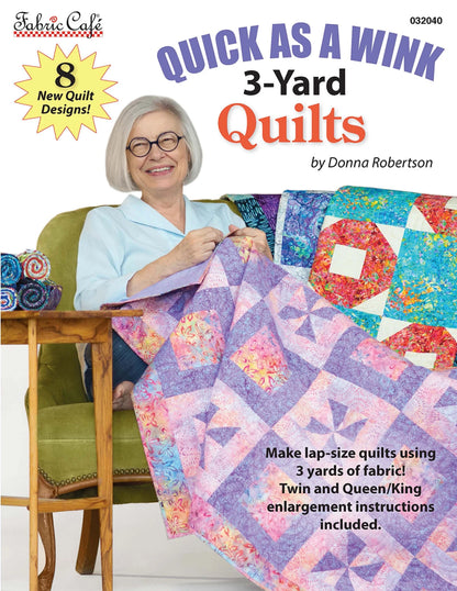 Smiling older woman with gray hair and glasses sits on a green chair, holding a colorful patchwork quilt. Text: “Quick As A Wink 3-Yard Quilts by Checker Distributor”—features 8 easy new designs with instructions included.