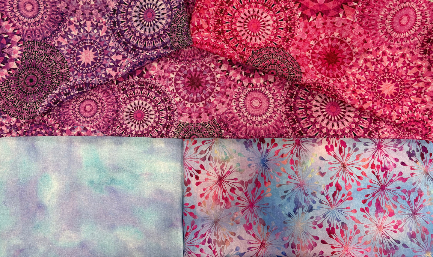 The Quilted Joy Pink Puffs 3 Yard Quilt Top Bundle includes four cotton squares: two with mandala-style pink/purple patterns, one pastel blue/purple wash, and one with pink/blue leafy bursts—ideal for Fabric Cafe quilt patterns.