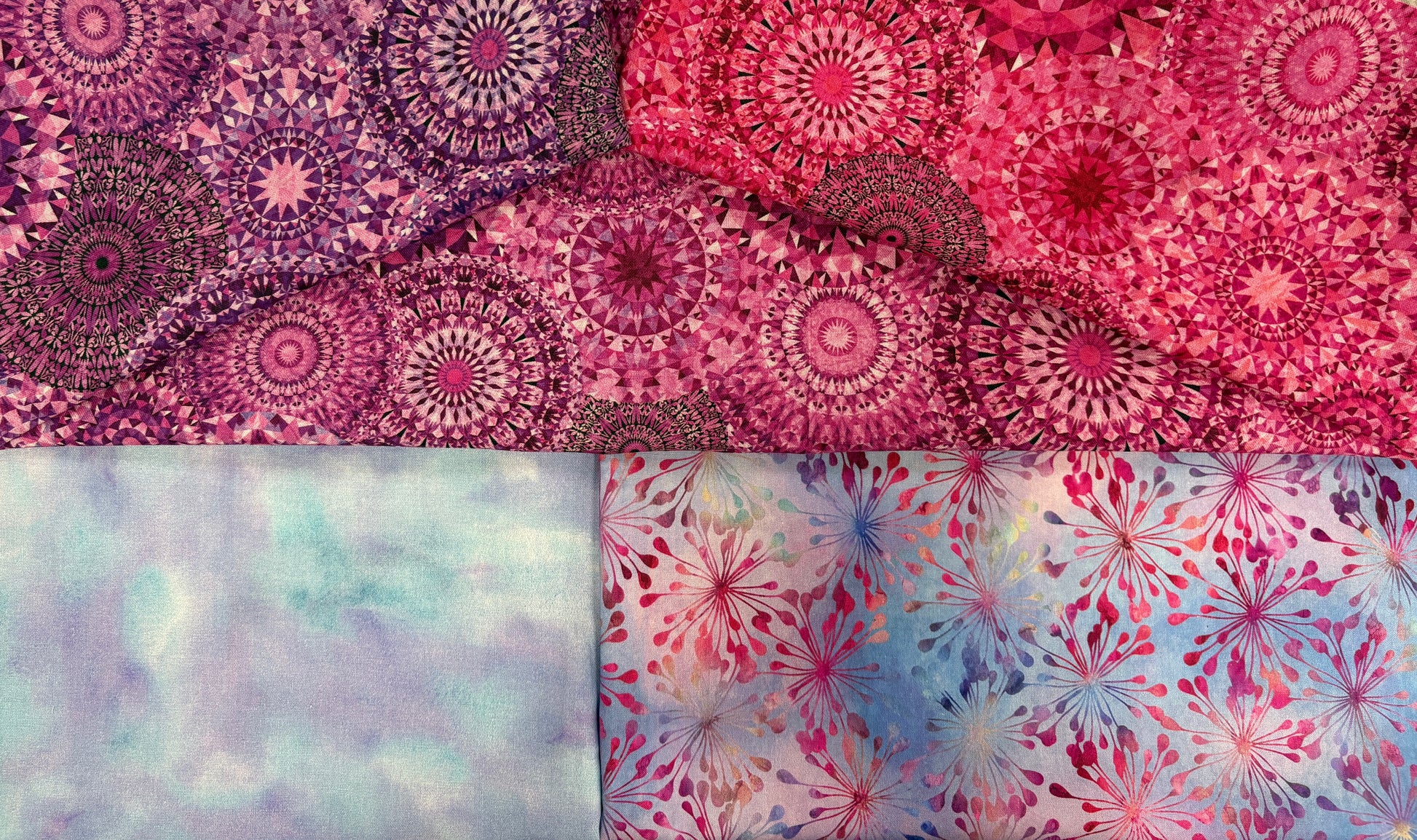 The Quilted Joy Pink Puffs 3 Yard Quilt Top Bundle includes four cotton squares: two with mandala-style pink/purple patterns, one pastel blue/purple wash, and one with pink/blue leafy bursts—ideal for Fabric Cafe quilt patterns.