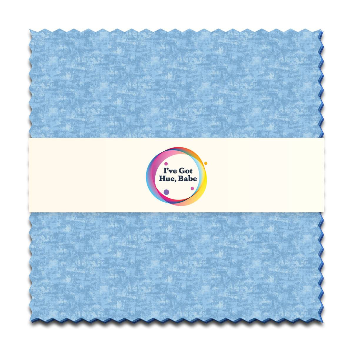 The "I've Got Hue, Babe Blue Moon 5\" Squares" by Jaftex - Henry Glass Fabrics feature light blue textured fabric with zigzag edges and a central band showing a colorful logo—ideal for charm packs or quilt squares.