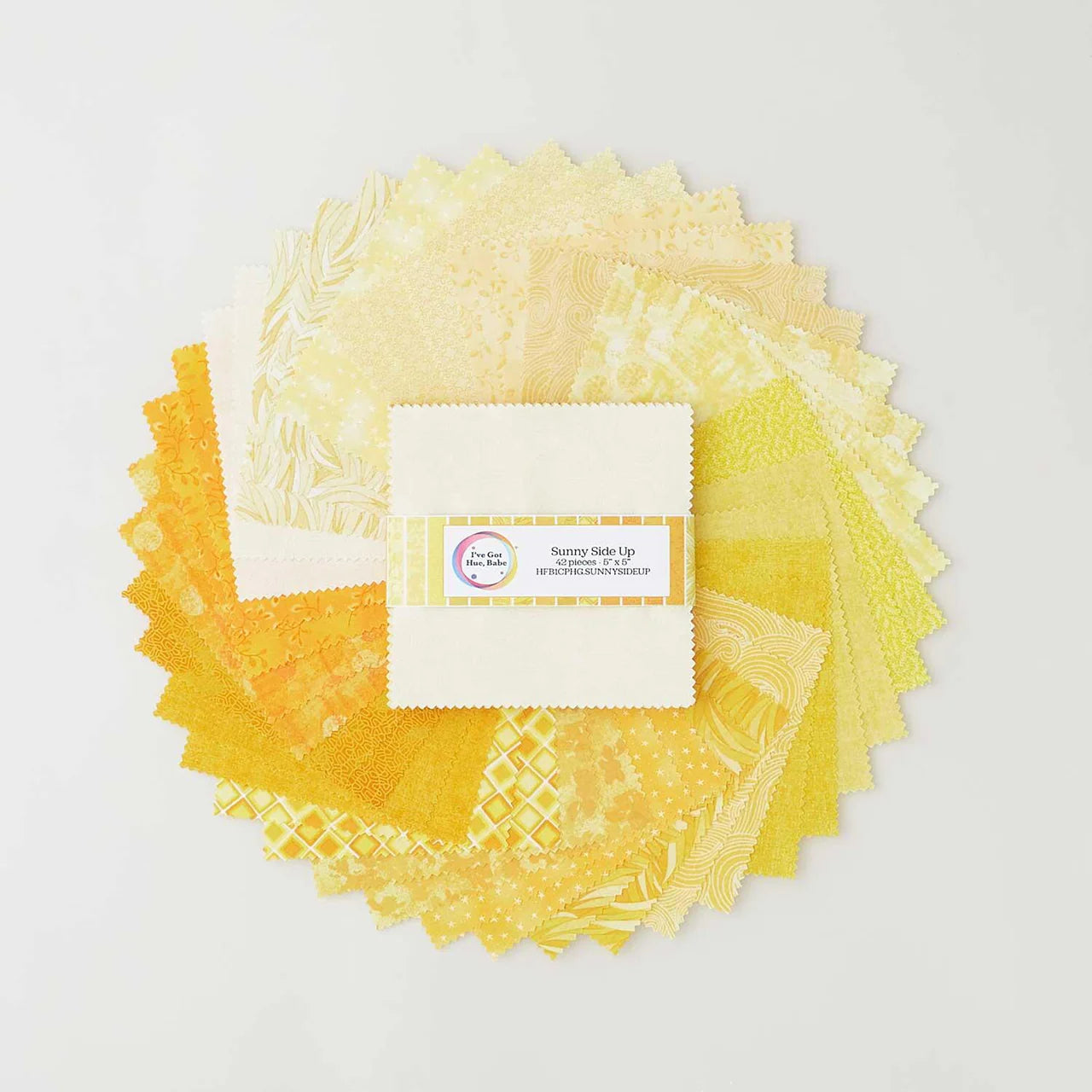 A circular arrangement of Jaftex - Henry Glass Fabrics I've Got Hue, Babe Sunny Side Up 5" Squares is shown on a white background, with a neatly stacked and banded charm pack of the same fabric in the center.
