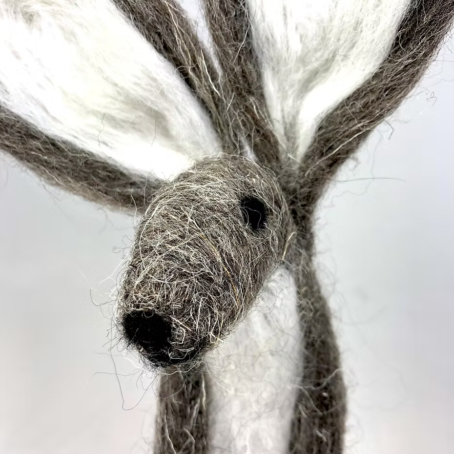 Close-up of a handmade Grey Hare, crafted from wool using the Feather Felts Needle Felting Kit (No Foam). The figure features large ears, a pointed snout, and black nose and eyes, displayed against a plain background.