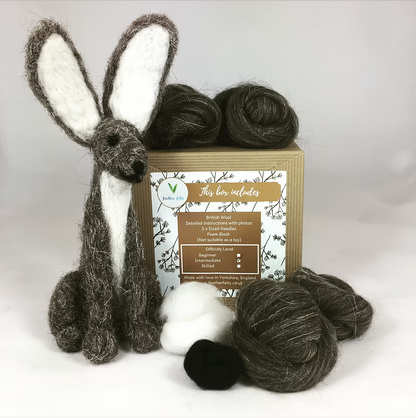 The Feather Felts Grey Hare - Needle Felting Kit (No Foam) includes wool and instructions, with a handmade felt hare featuring large white ears—ideal for beginners starting needle felting projects.