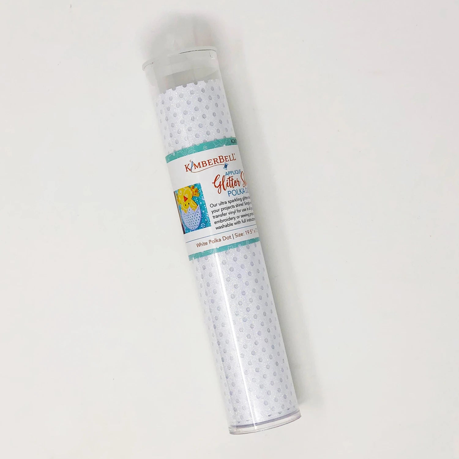 A clear cylindrical container holds a Kimberbell White Polka Dot Applique Glitter Sheet, ideal for machine embroidery or as an iron-on glitter sheet. The label shows branding and a colorful project example.