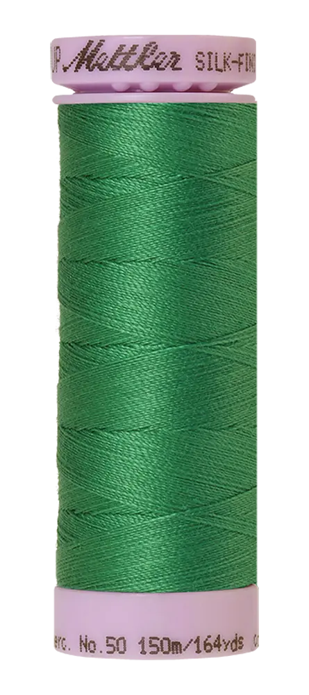 A spool of Mettler Cotton Silk Finish 50wt thread in Kelley green, with a light pink plastic top and bottom. The label shows 150m (164yds).