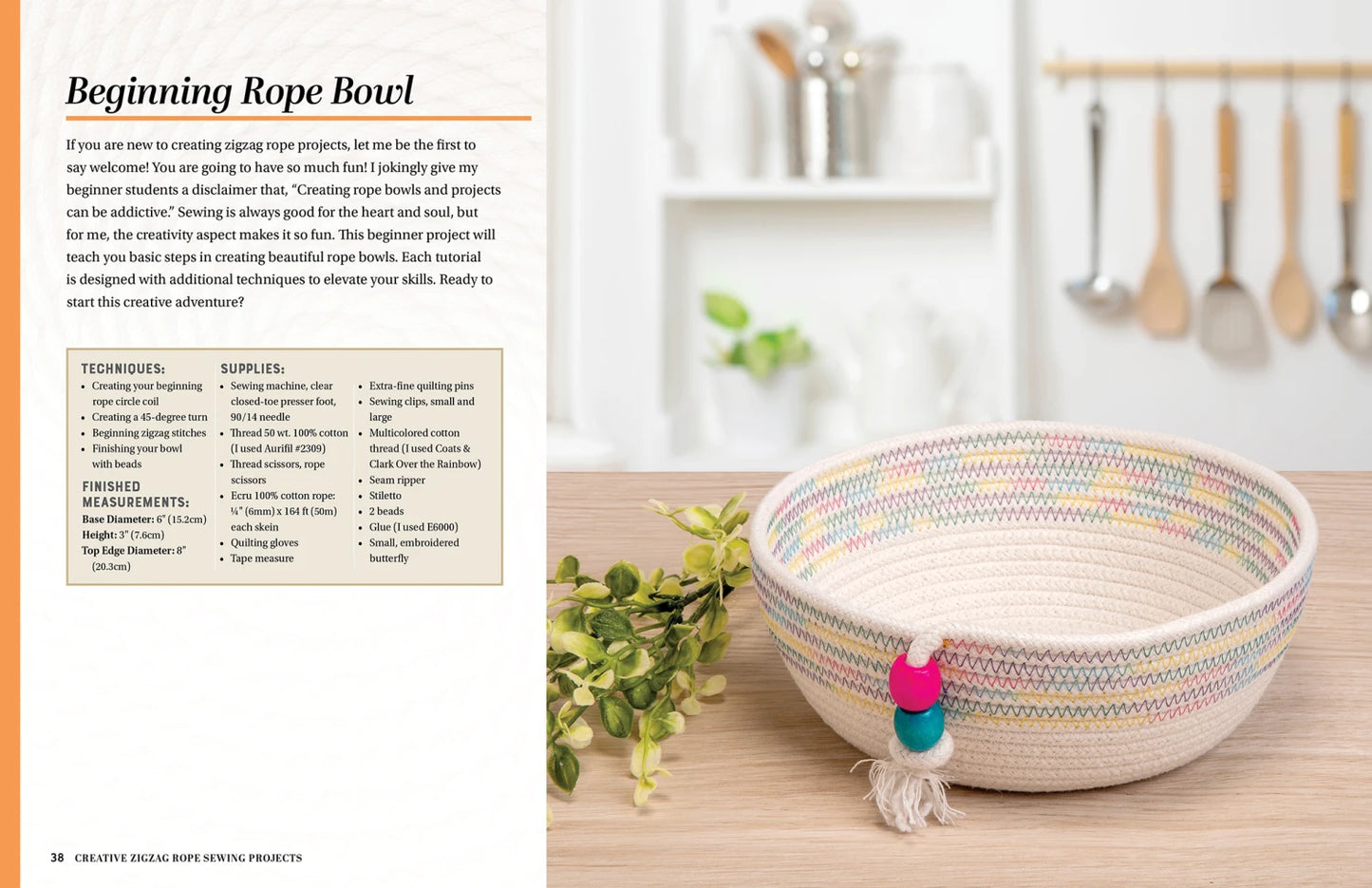 The Creative Zigzag Rope Sewing bowl by Checker Distributor, featuring pink and turquoise beads and crafted with a zigzag stitch, sits on wood. Behind it, kitchen utensils hang on hooks and two potted plants add charm to the wall.