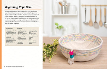 The Creative Zigzag Rope Sewing bowl by Checker Distributor, featuring pink and turquoise beads and crafted with a zigzag stitch, sits on wood. Behind it, kitchen utensils hang on hooks and two potted plants add charm to the wall.