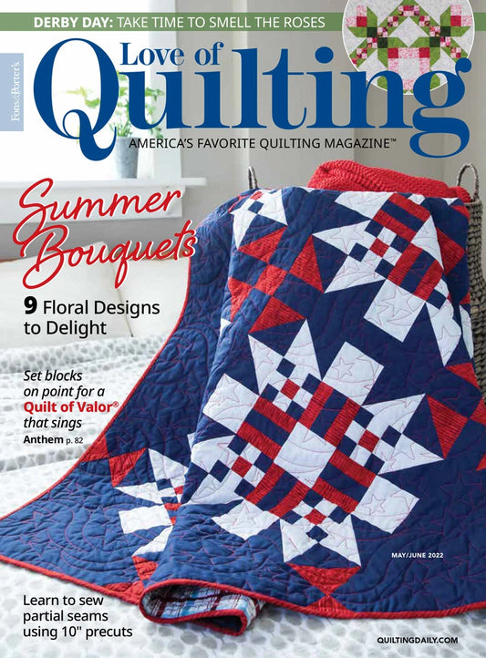A red, white, and blue star-patterned quilt is draped over a white chair. The cover of the autographed Love of Quilting Magazine May June 2022 Edition by quiltedjoy features summer florals and tips for sewing with 10 precuts.