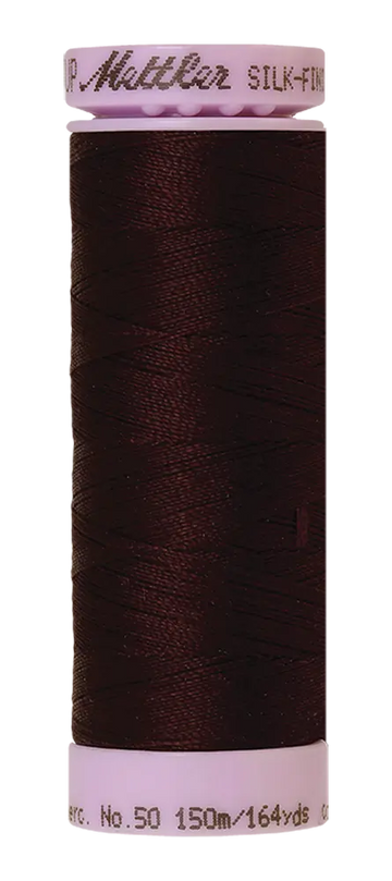 A spool of Mettler Cotton Silk Finish 50wt thread in Mahogany, 150m/164yds, ideal for cotton sewing and quilting projects.