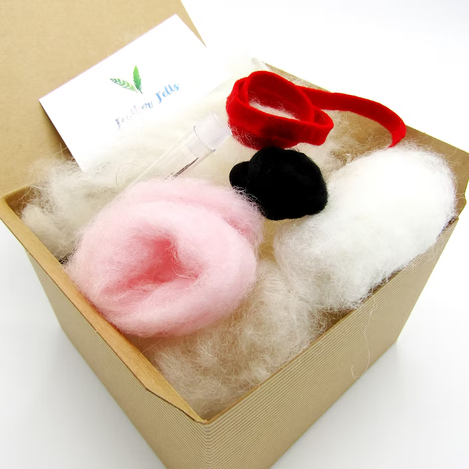 The Feather Felts White Mouse Needle Felting Kit (No Foam) includes white wool, pink/black/white felt, a red pipe cleaner, needle felting instructions, a clear tool, and a green-leaf card—ideal for crafting your own felted mouse.