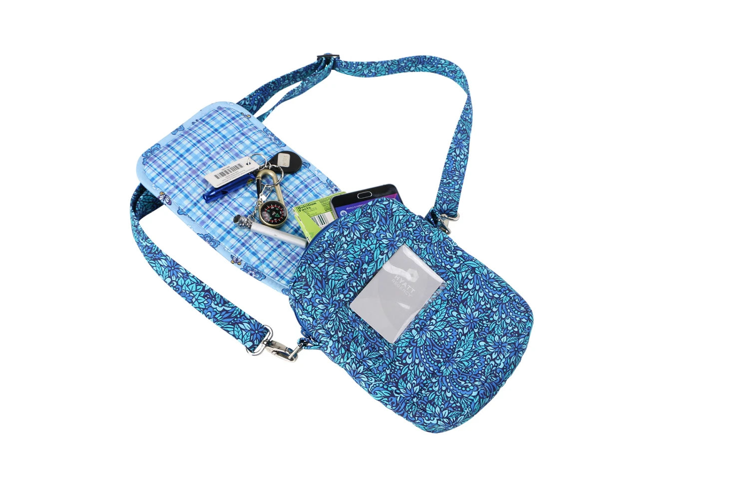 The On the Go 2.0 Quilt Pattern blue crossbody bag, shown on a white background, features a clear ID window and holds keys, a pen, cards, and a smartphone.