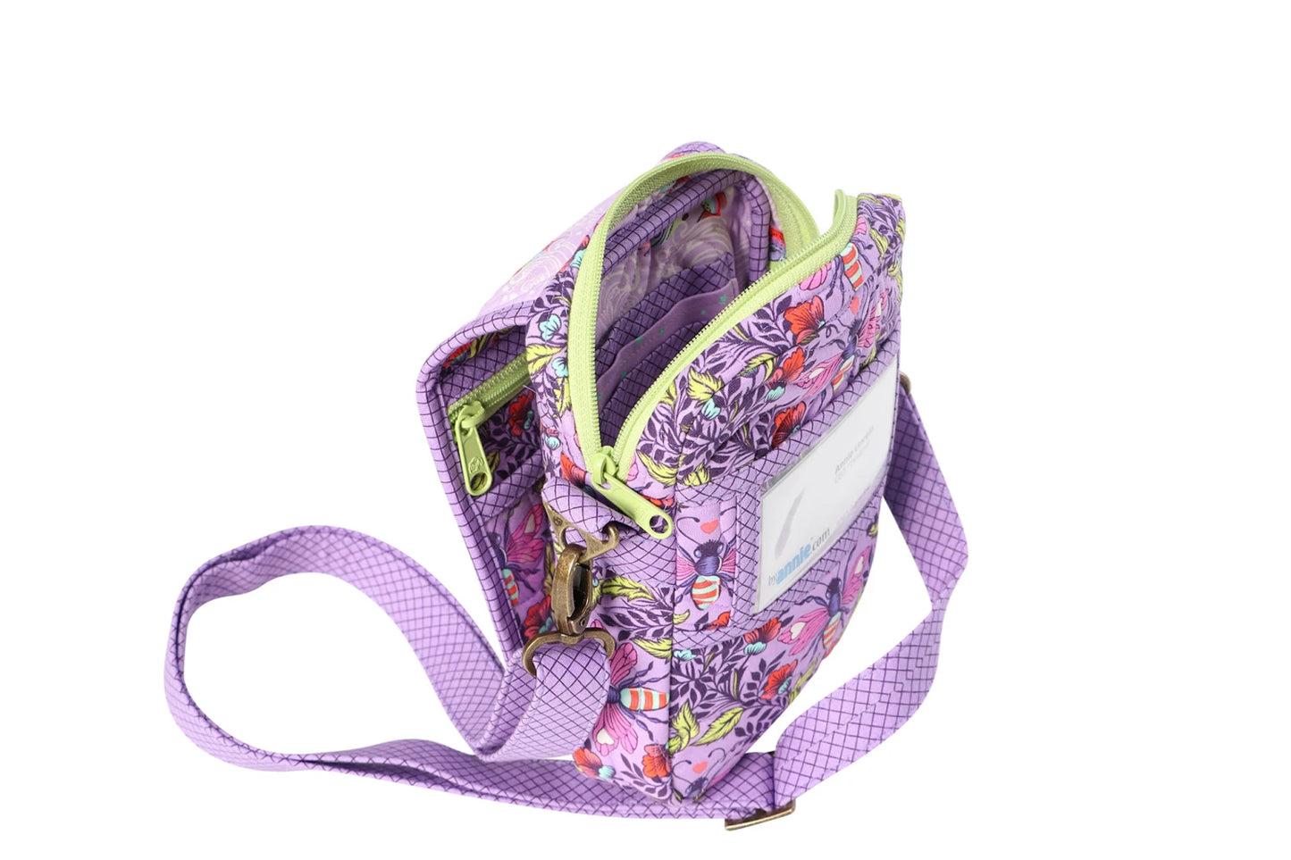 The On the Go 2.0 Quilt Pattern is shown as a small crossbody bag with a purple strap, vibrant floral print in pink, green, and orange, multiple zippered compartments, and a clear front window against a white background.