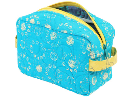 A blue quilted bag with white circles, yellow zipper, and side handle—perfect as a cosmetic pouch or for practicing zipper installation, just like in the Quilted Joy Easy Does It Bag Class.