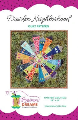 Cover of the Dresden Neighborhood Mini Quilt Pattern by Brewer Sewing. Features colorful wedge-shaped houses in a circle on a green background, inspired by the classic Dresden plate block. Includes branding and finished quilt size details.