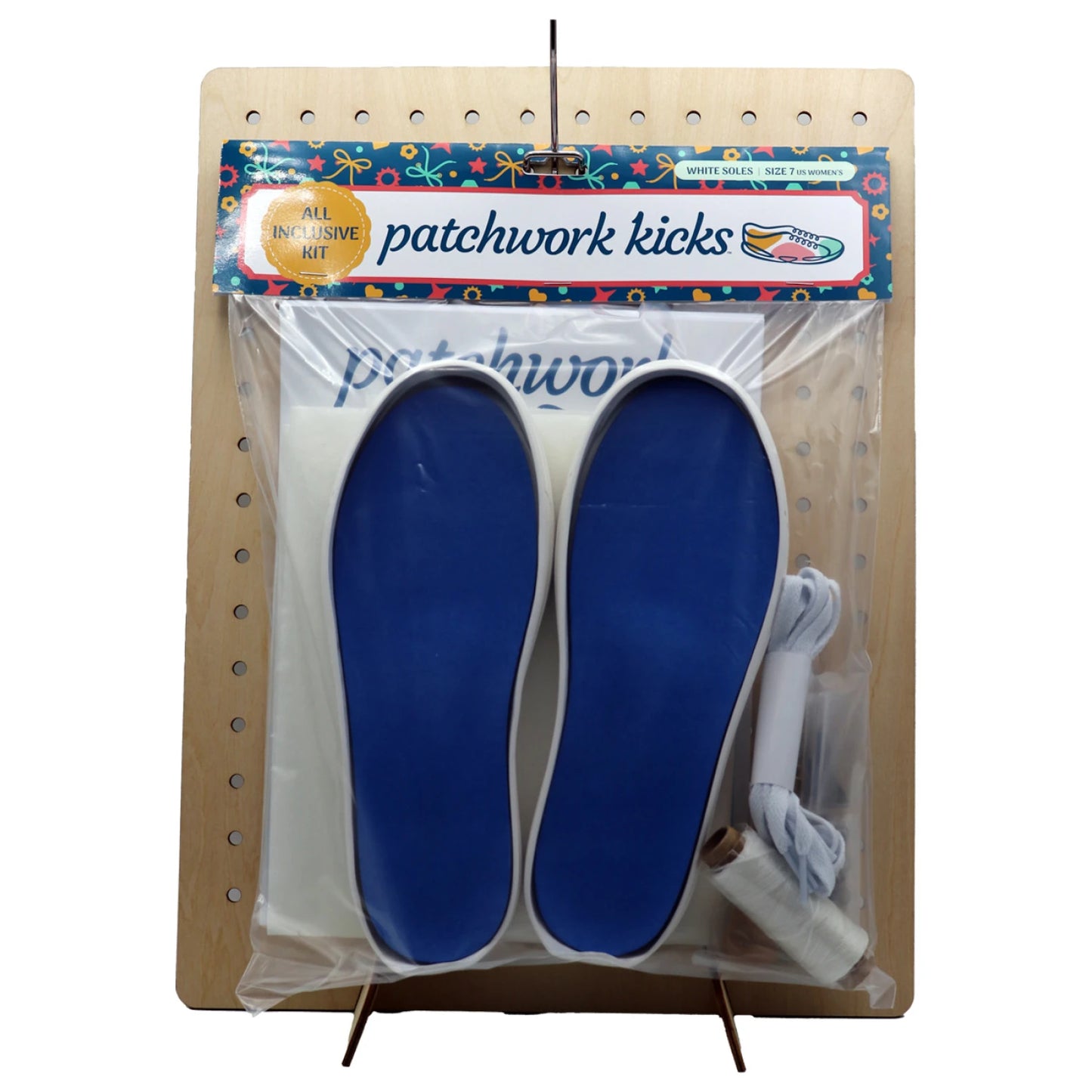 The Patchwork Kicks White Shoe Kit by Checker Distributor is displayed on a pegboard, showing blue and white soles, laces, thread spool, and beginner sewing materials in clear packaging.