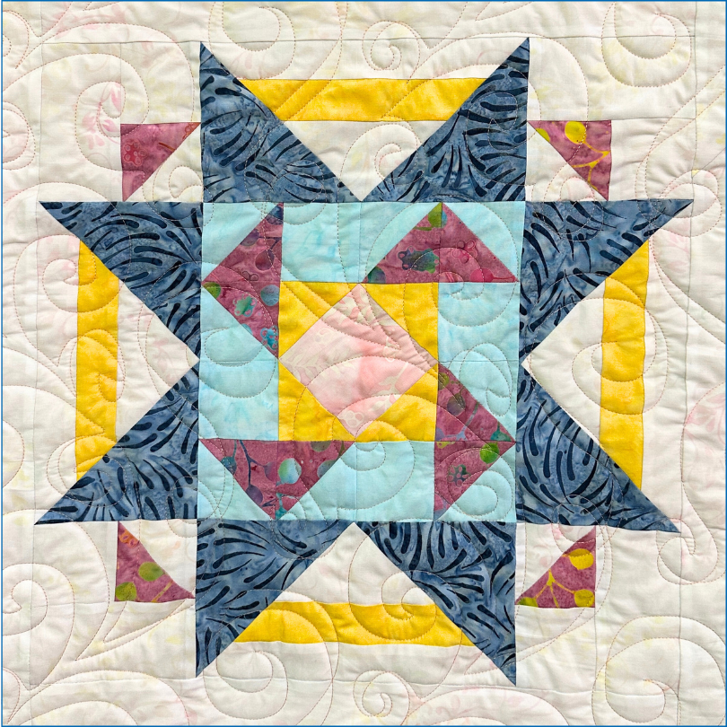 The Quilt Fairy Dreams Block of the Month features a vibrant star pattern with blue, yellow, purple, and pink batik shapes on cream, accented by swirling quilted stitching—perfect inspiration for your next quilting class.