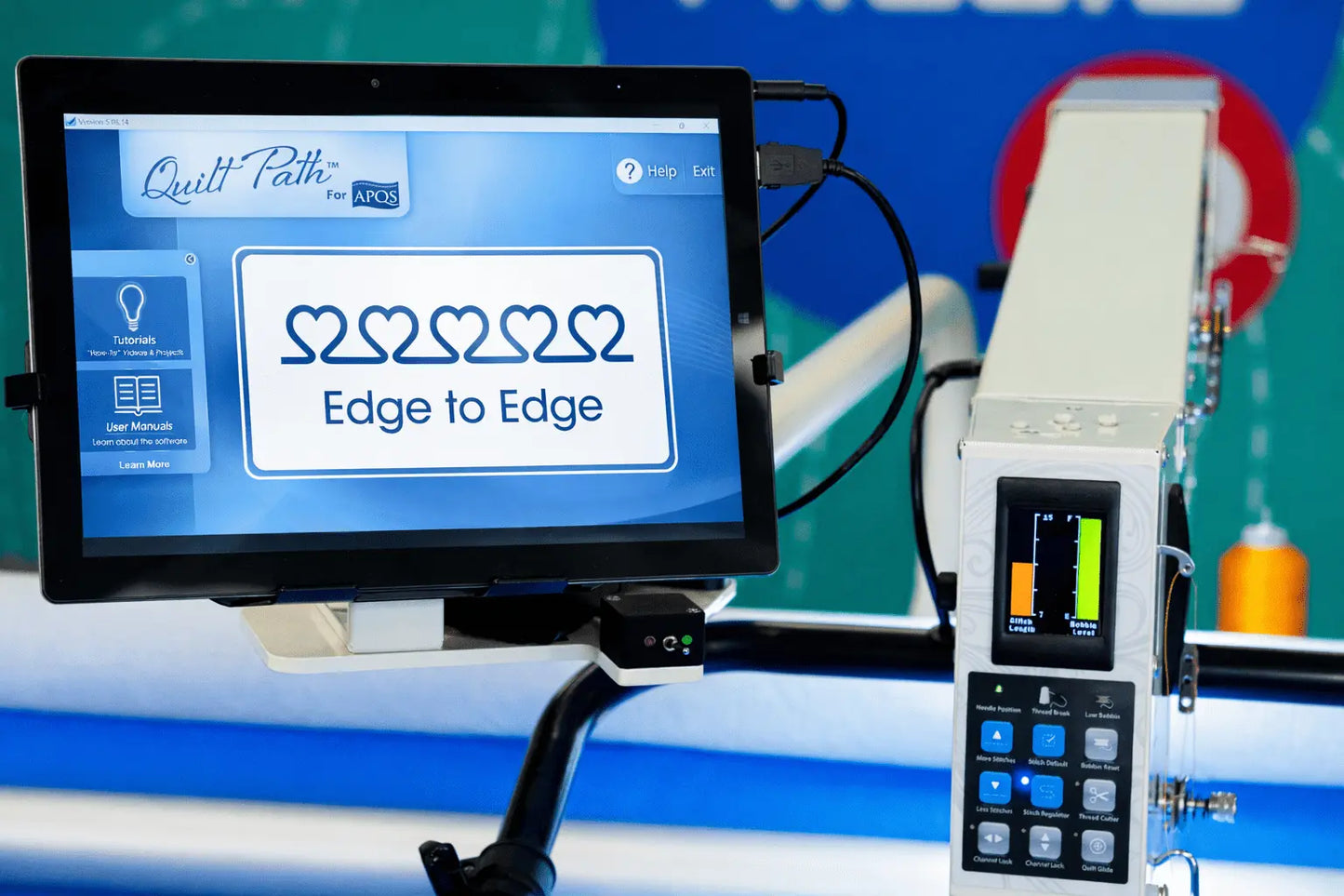 A digital screen shows “Edge to Edge” with five linked hearts on the APQS Quilt Path Robot Computer by APQS, featuring a control panel with buttons and a small color display for precise computerized quilting.