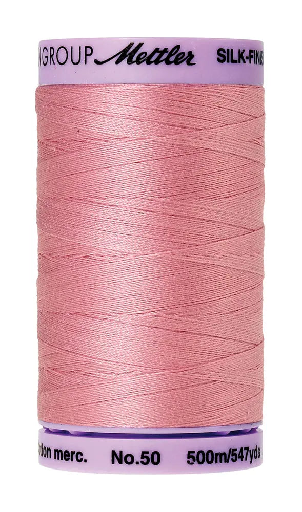 A spool of Mettler Cotton Silk Finish 50wt 500m in Rose Quartz, perfect for quilting and sewing projects, labeled “Mettler” with a purple cap.