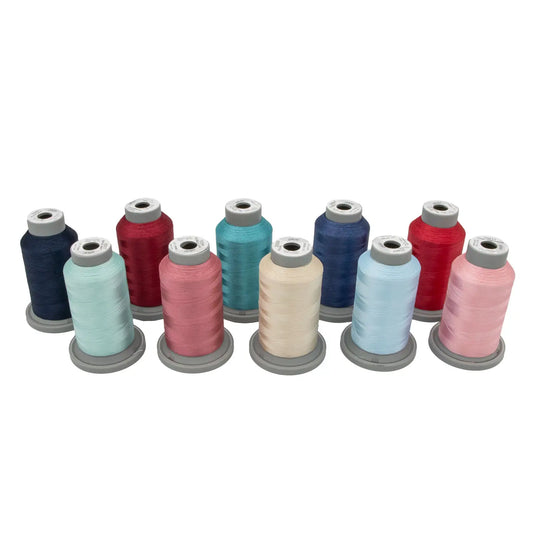 Nine spools of Hab+Dash by Fil Tec thread in assorted colors, including blue, red, pink, and cream, are displayed in a row—ideal for machine embroidery with the Kimberbell Star Spangled Beauty Glide Thread Bundle.
