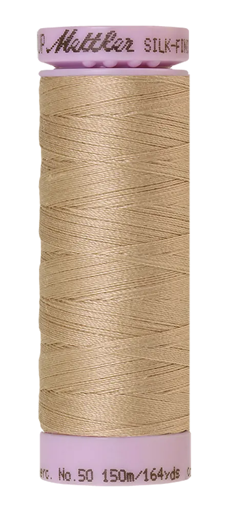 A spool of Mettler Cotton Silk Finish 50wt 150m Straw, with pink ends and 150 meters of cotton thread, is displayed against a white background.