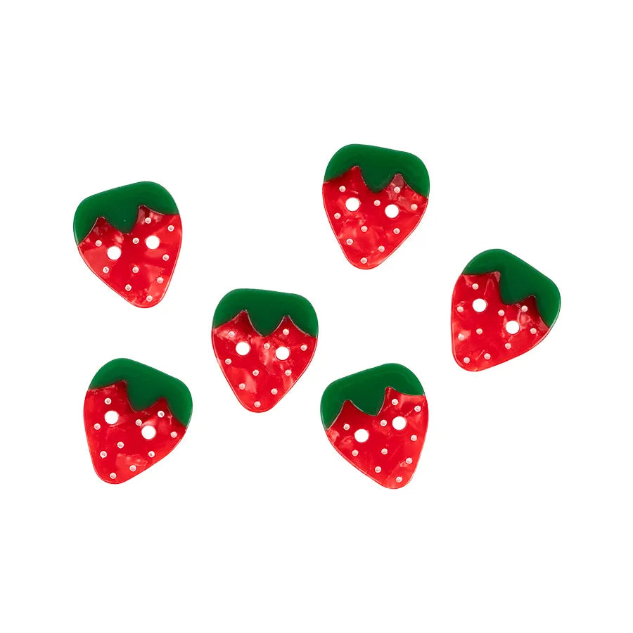 Six 1" large strawberry buttons by Checker Distributor, plant-based acetate with red bodies, green tops, and white polka dots, are scattered on a white background—perfect sewing project accents.